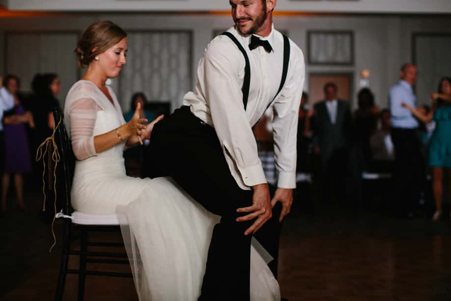 Groom dancing on bride as she sits in a chair for garter removal with music provided by Our Dj Rocks at the Lake Mary Westin