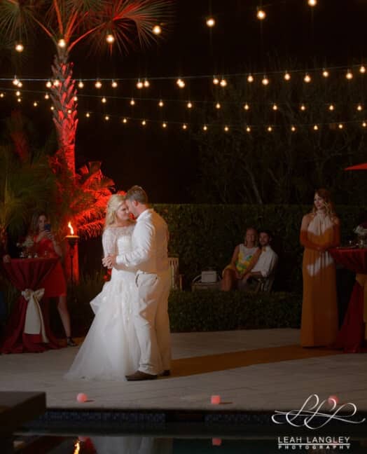 Bride and groom first dance outside under market lights and red uplighting