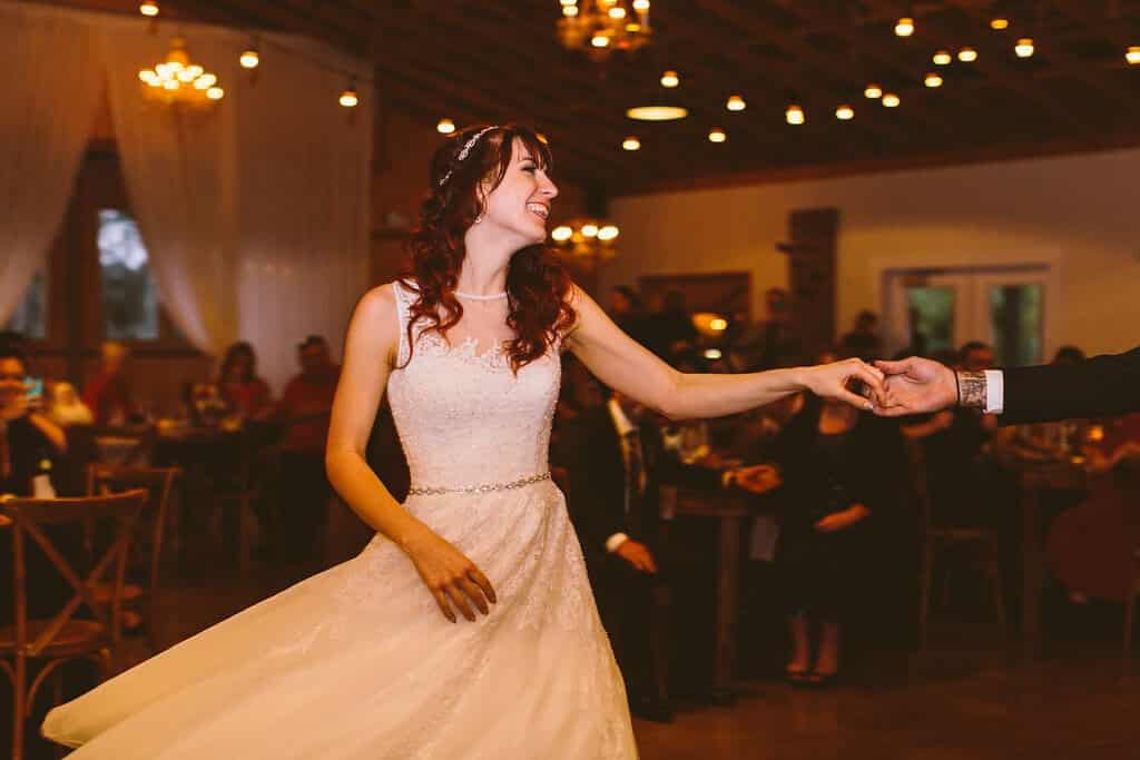 Bride dancing at wedding at Up the Creek Farms in white lace wedding dress