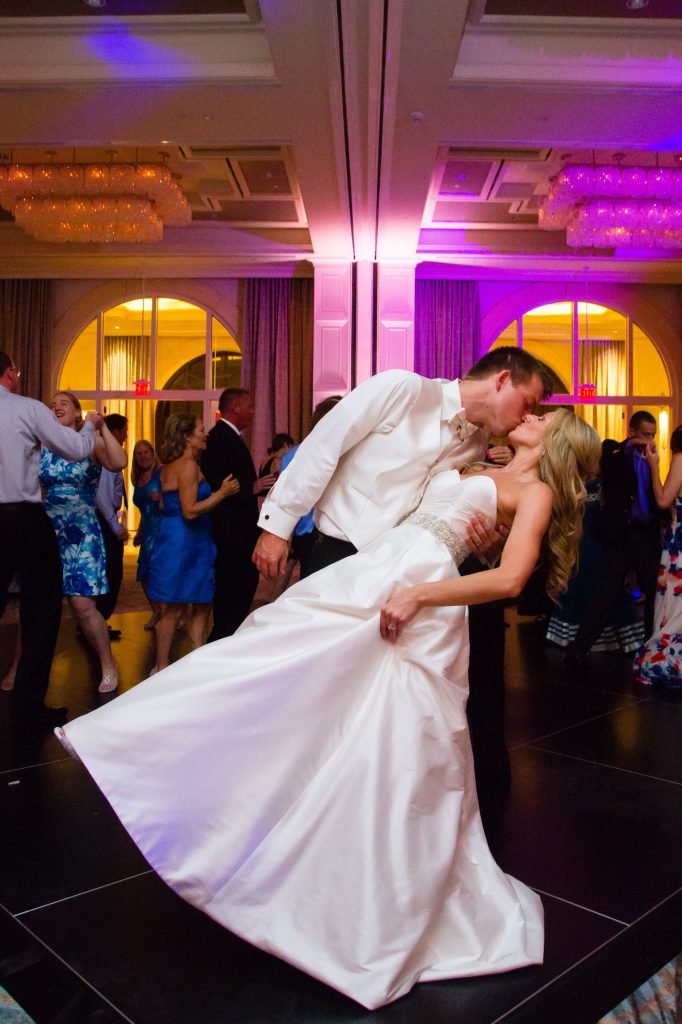 Four Seasons wedding bride and groom dip and kiss on dance floor with blush pink uplighting
