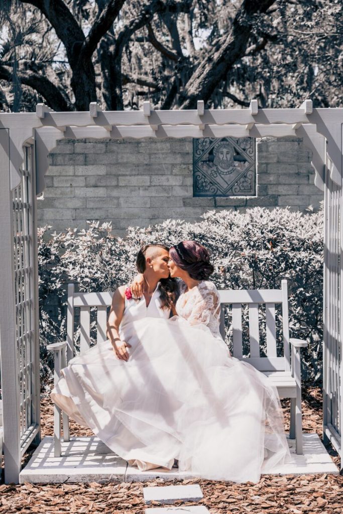 brides sharing kiss on bench