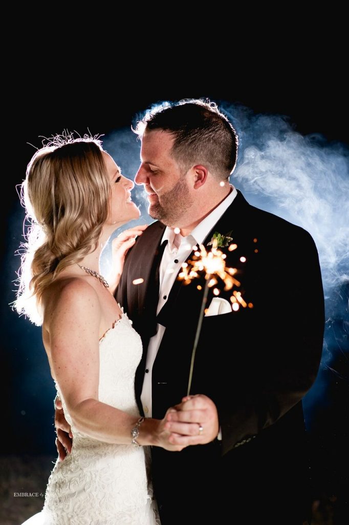 bride and groom backlit and holding sparkler