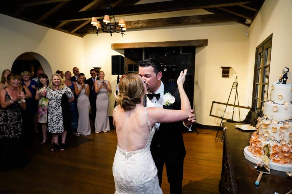 newlyweds kissing next to wedding cake