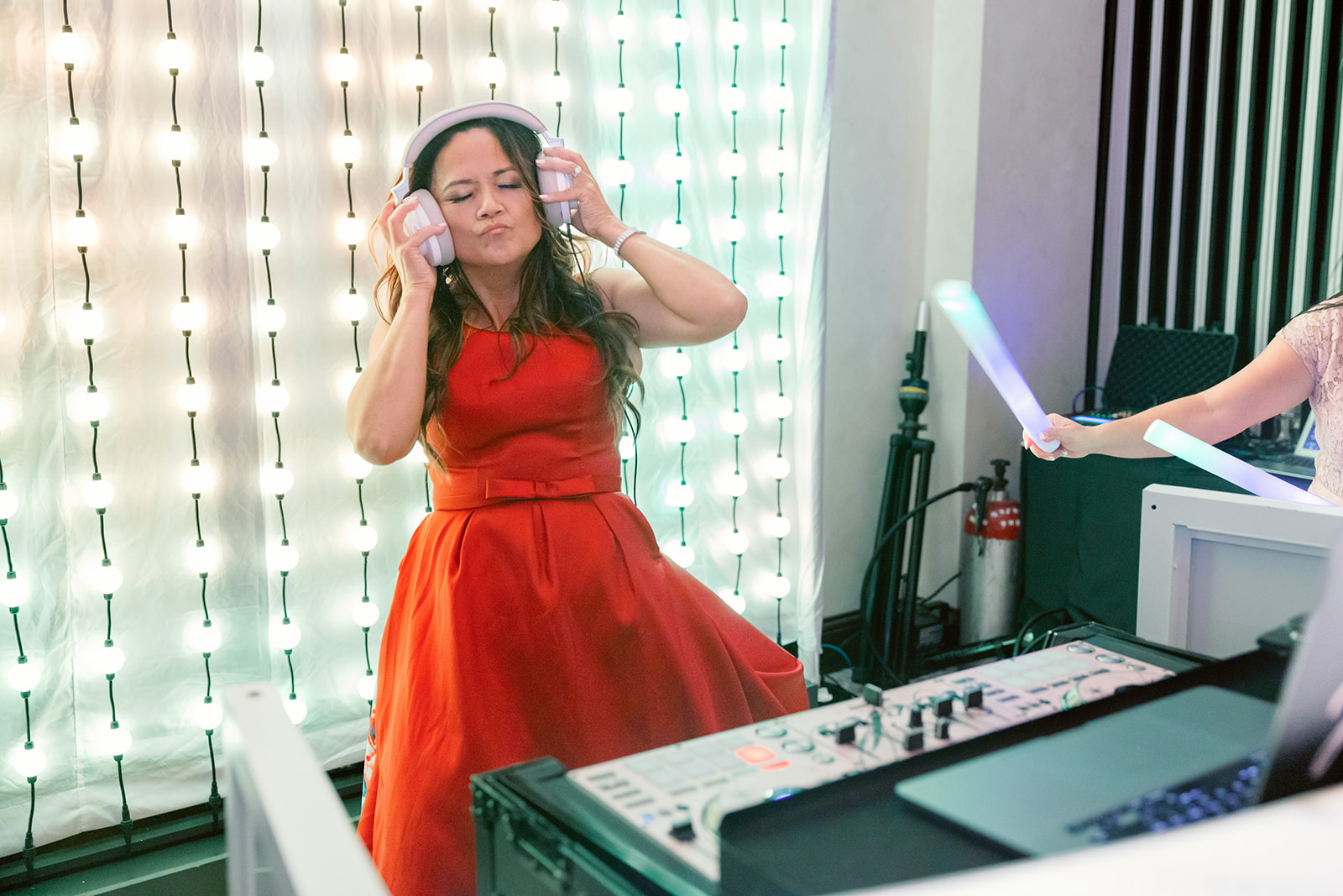 woman in red dress wearing headphones behind the dj booth