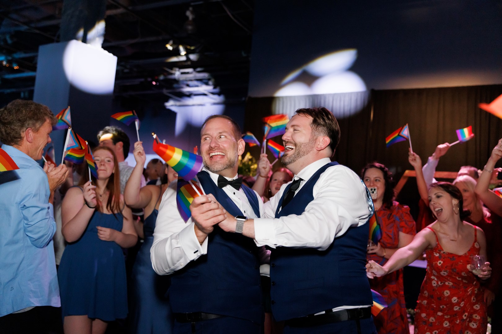 Andrew and Joe dancing at their wedding while holding pride flags