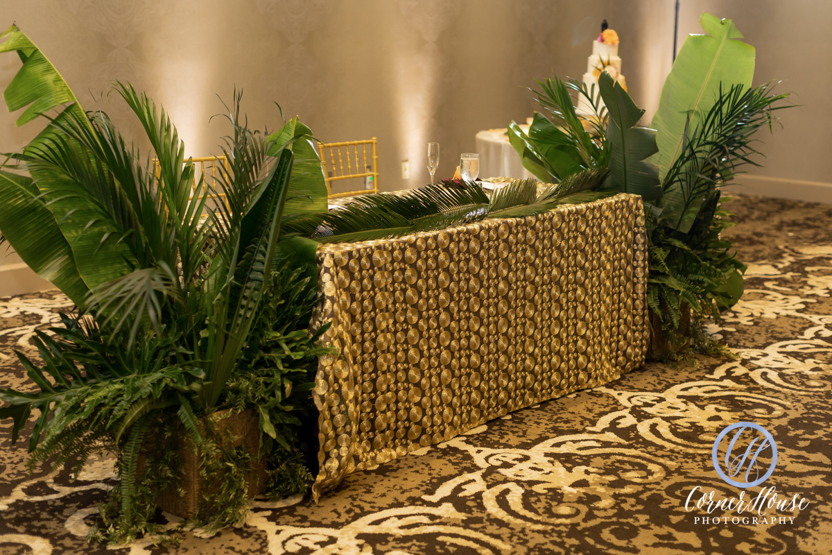 Matt and Chance's sweetheart table with gold tablecloth and tropical greenery