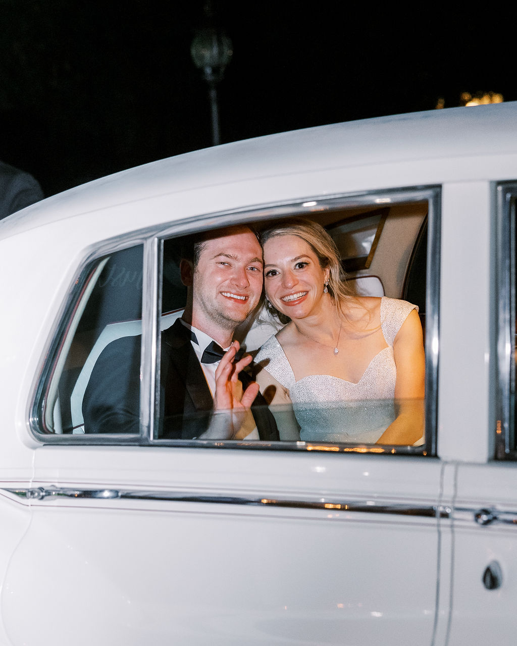 bride and groom looking out car window after wedding