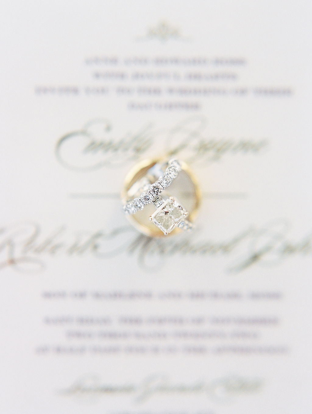 bride and groom wedding rings on blurred invitation
