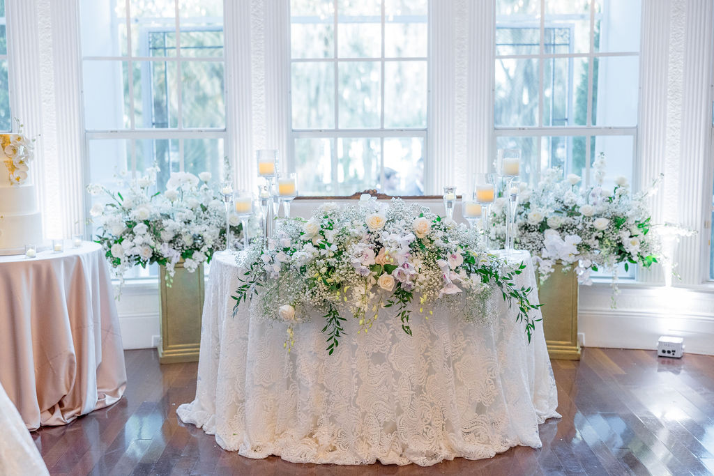 Sweetheart table with white tablecloth covered in florals