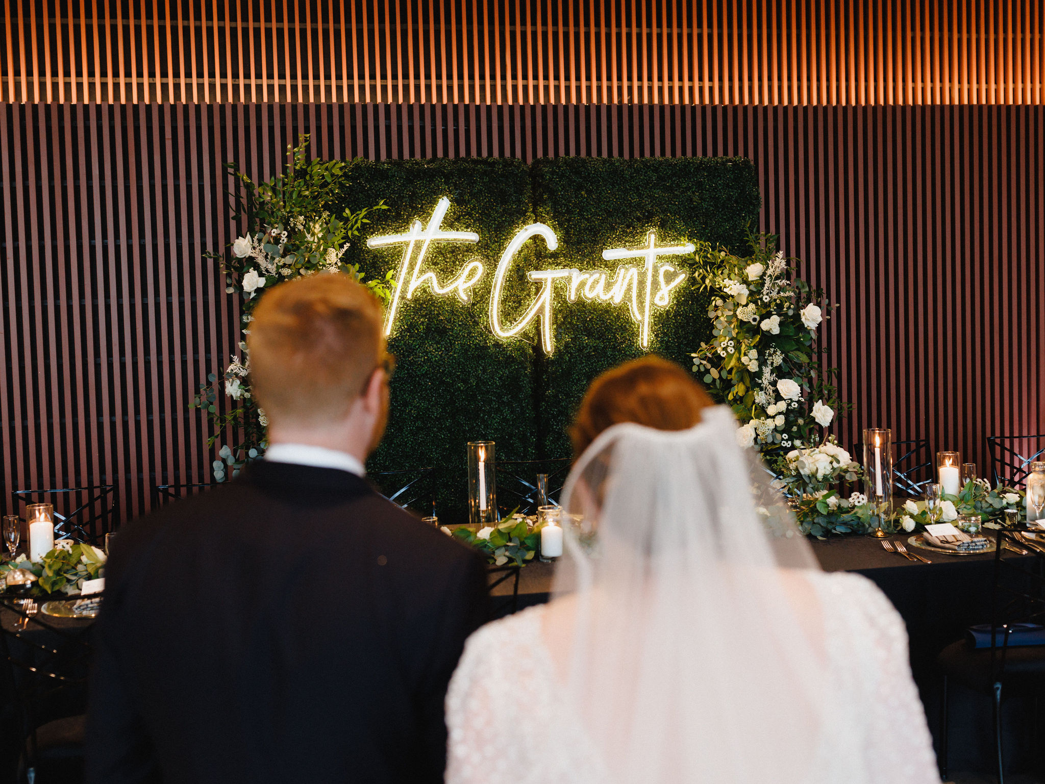 Katie and Bobby see their sweetheart table with neon sign reading "The Grants"