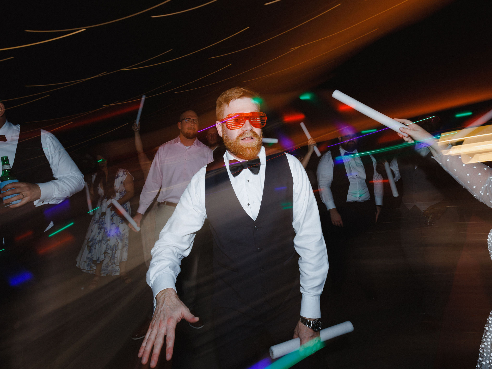 Bobby wearing sunglasses and carrying a glowstick on the dance floor at his wedding