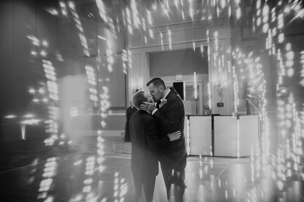 two grooms share a kiss on the dance floor