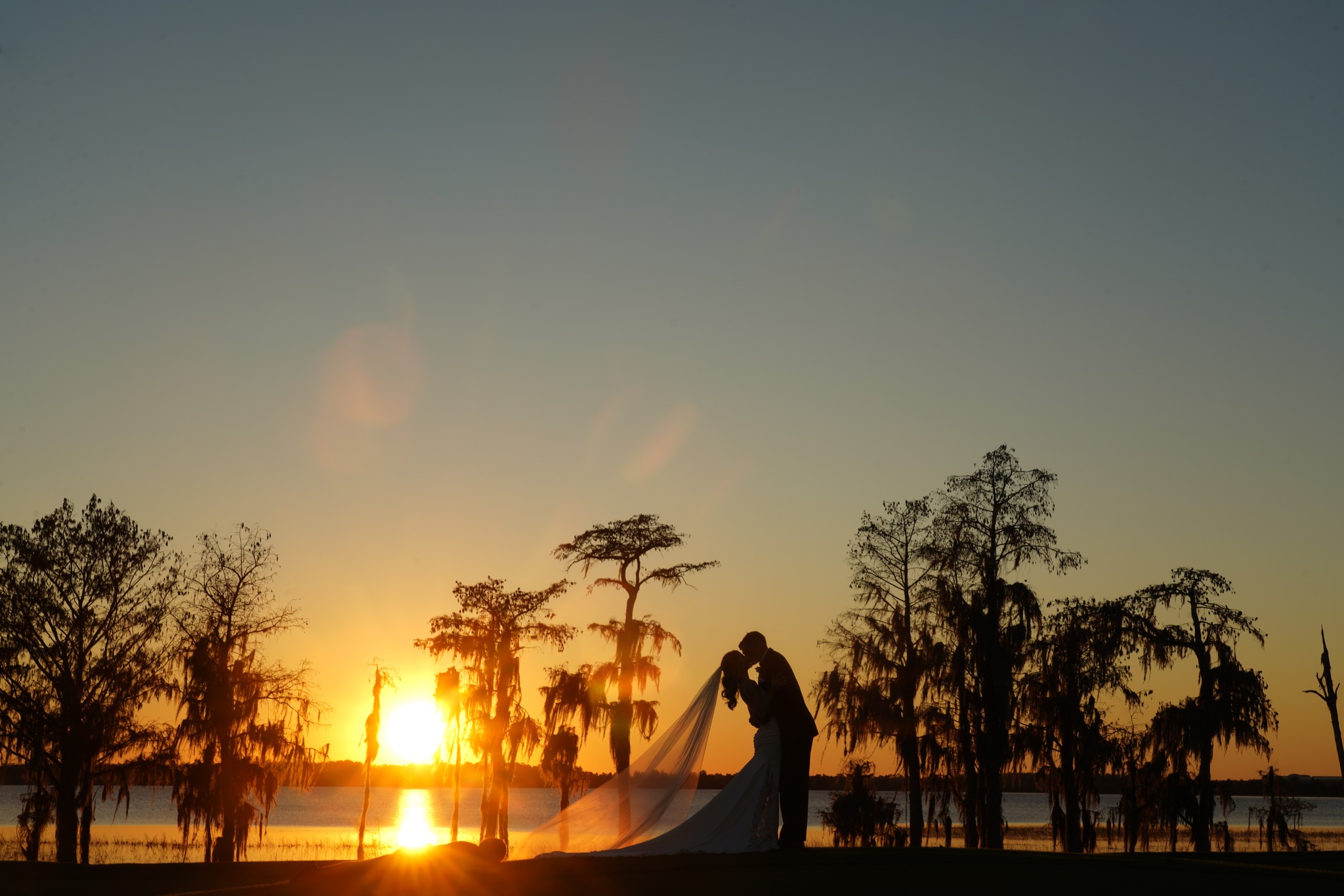 Cici and Sam kiss while silhouetted by the sunset