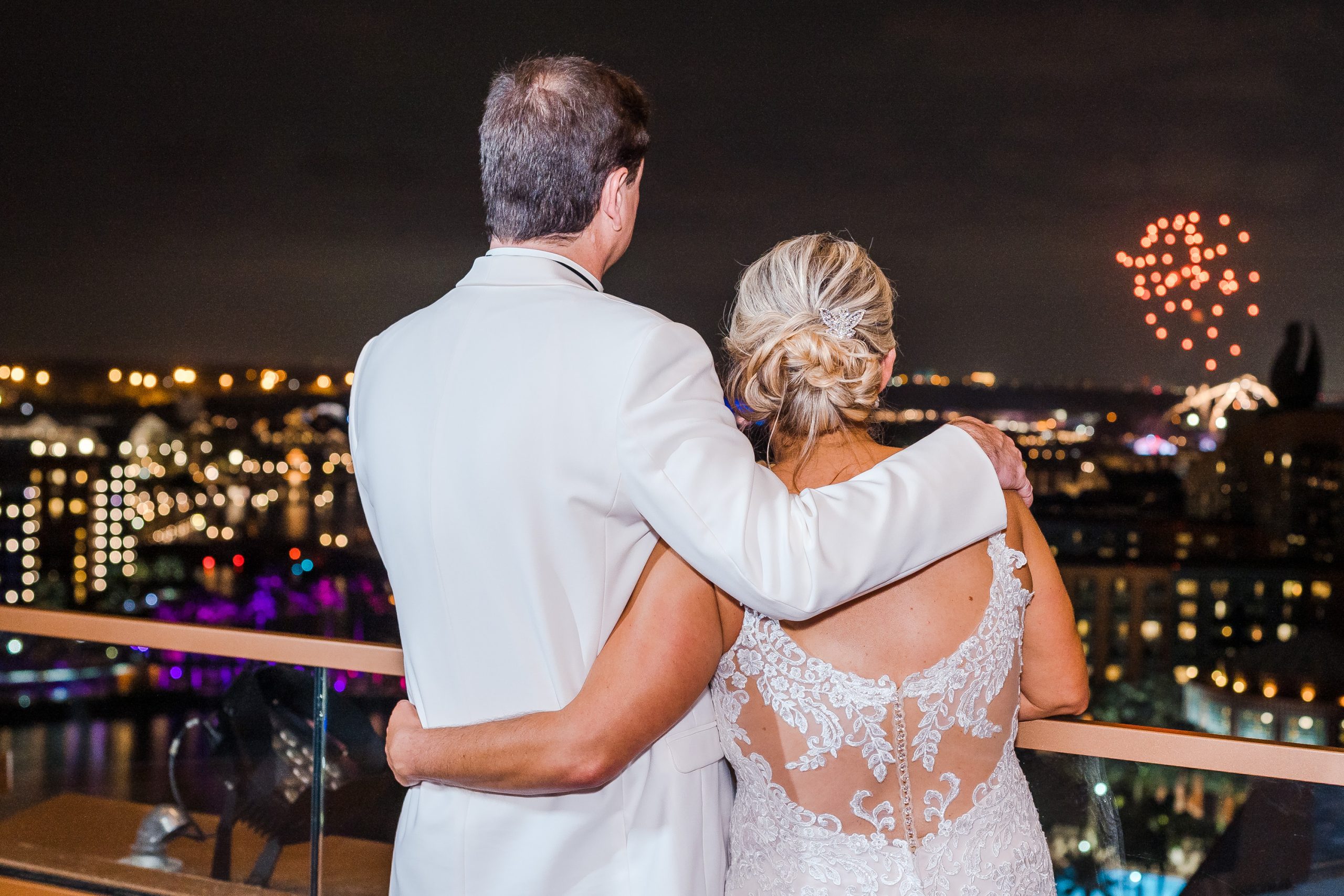 bride and groom watching Disney fireworks from balcony