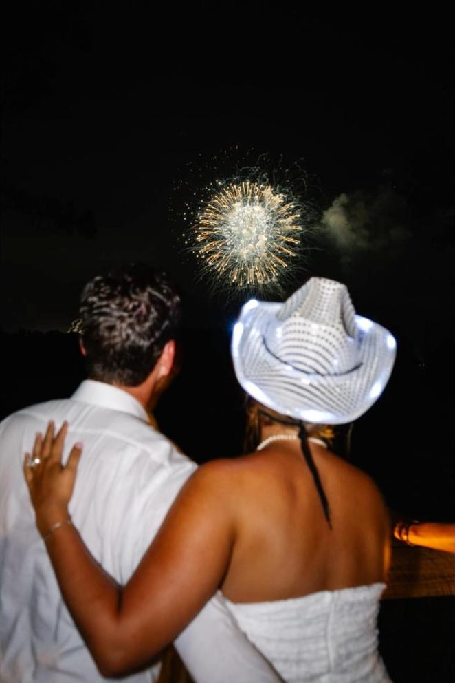 Newlyweds watching fireworks together, seen from behind