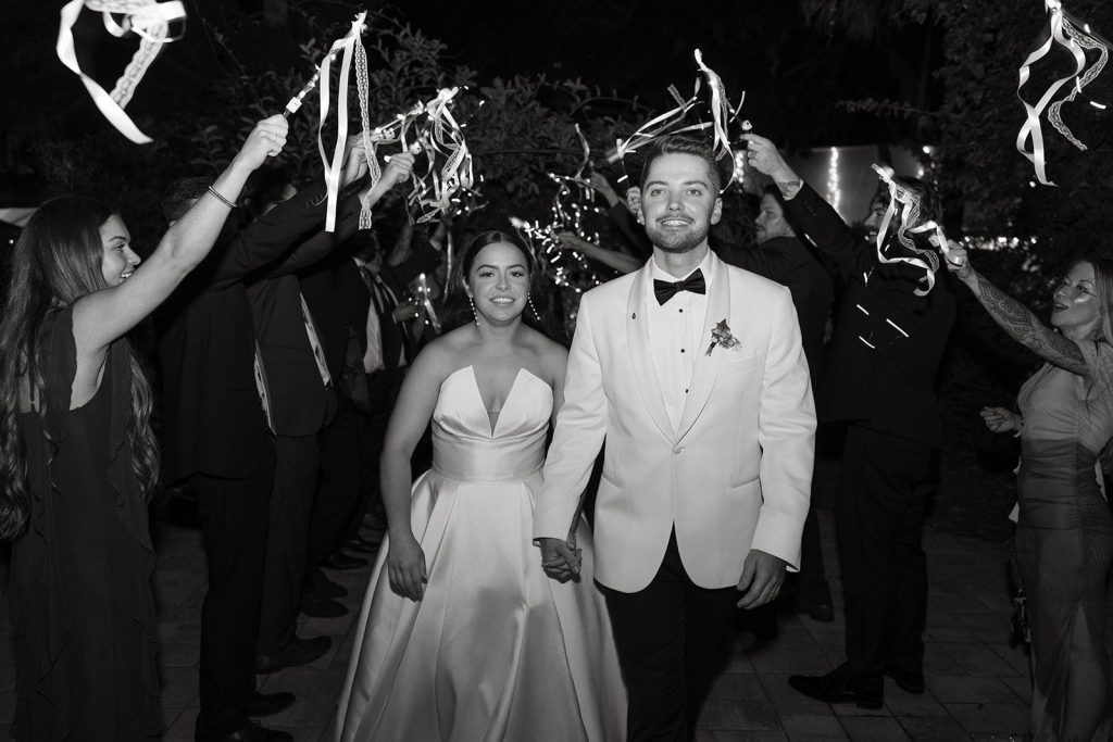 Grand exit with guests holding ribbon wands at a Victoria 1883 wedding in New Smyrna Beach