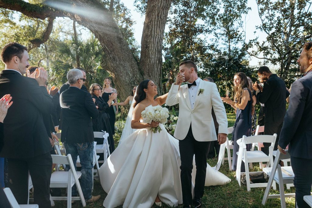 Newlyweds recessing through applauding guests under a live oak at Victoria 1883