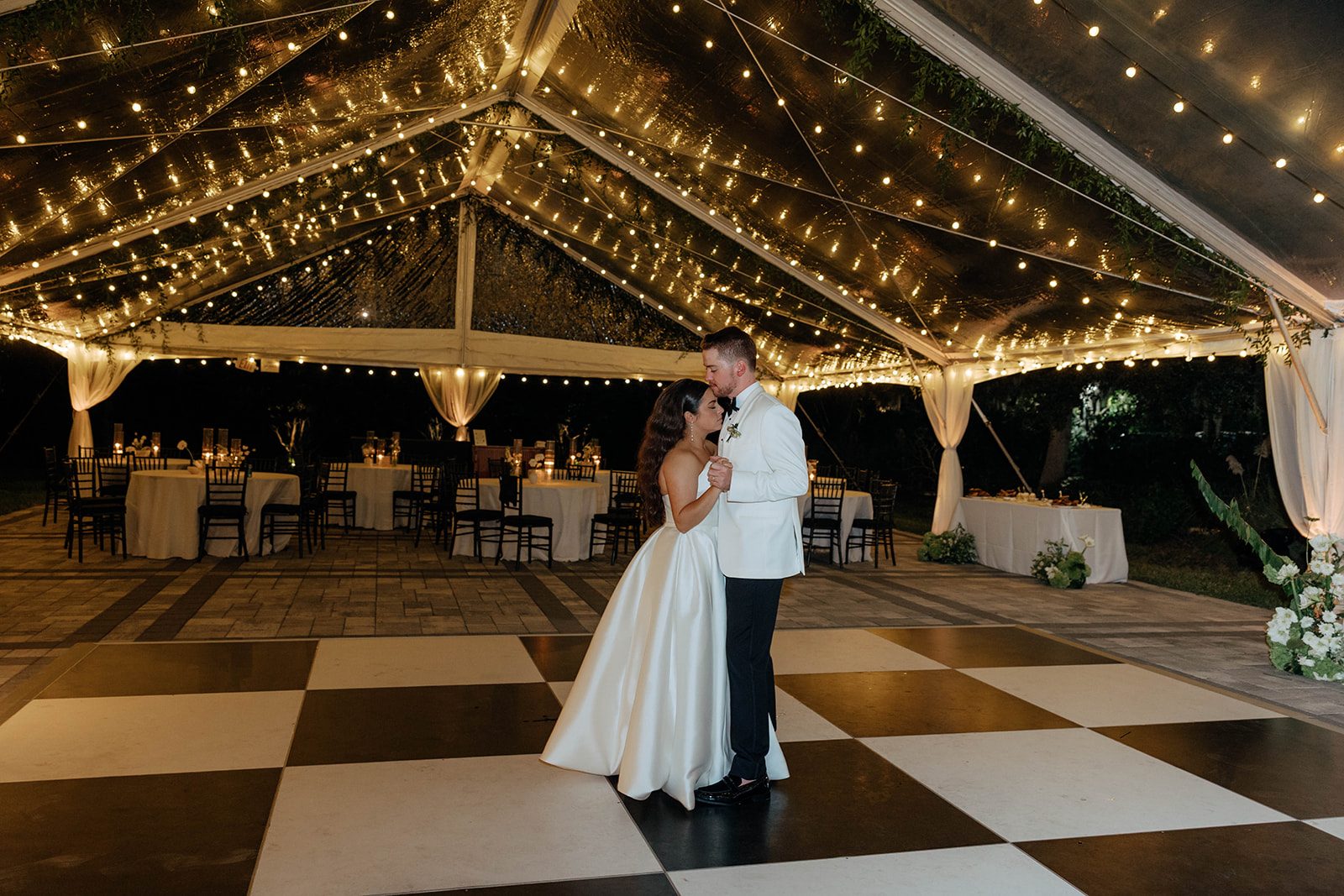 Kenzie and Andrew slow dancing under the string-lit clear tent at their Victoria 1883 wedding in New Smyrna Beach
